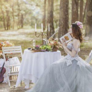 The bride is sitting at a decorated table in the forest