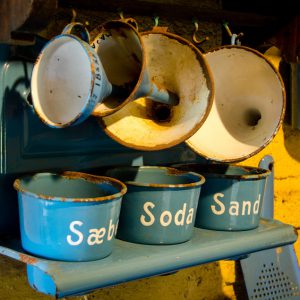 Old rusty blue pots on a shelf with funnels hanging above them