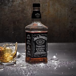 A bottle of Jack Daniels served in a glass with diamonds beneath it