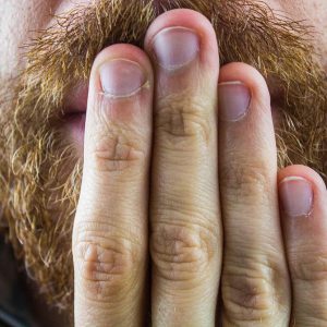 Man's mouth covered with fingers